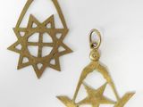 deux pendentifs en laiton ornés de symboles maçonniques, posés sur une surface blanche