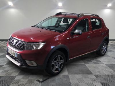 une photo d'une Dacia rouge garée sur un sol à damier