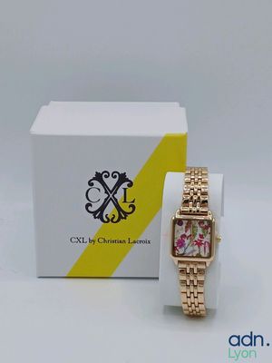 une photo d'une montre posée sur une boîte blanche, à côté d'une boîte jaune et blanche