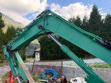 a large green excavator that is on the side of the road