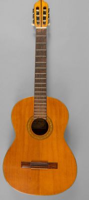 une vieille guitare en bois posée sur une surface grise