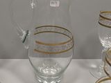 five glasses and a pitcher sitting on a table