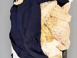 une valise noire contenant des vêtements, avec un chapeau posé dessus