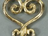 un gros plan d'une broche en forme de cœur ornée de volutes
