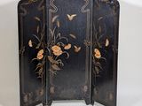 a black and gold screen with flowers and butterflies on it