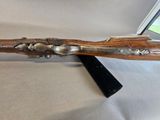 a rifle with a wooden handle on a white surface