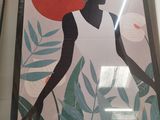 two framed art pieces of a woman with a red sun in the background