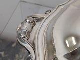 a silver plate with a silver handle on a table