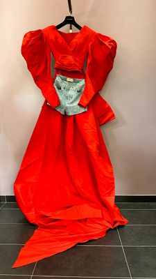 a red dress hanging on a hanger on a wall