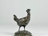 a bronze statue of a chicken standing on a base