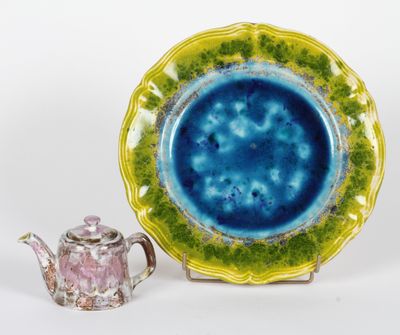 une assiette bleue et verte avec une théière à côté