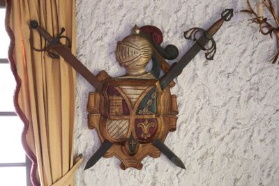 a picture of a wall mounted with two swords and a shield