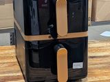 une friteuse à air chaud noire et dorée posée sur une table en bois