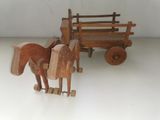 a small wooden horse pulling a wagon with a wooden horse