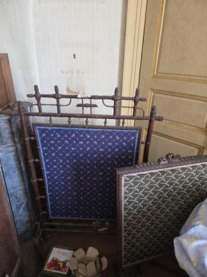 un lit recouvert d'une couverture bleue, avec une chaise à côté