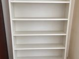 a white bookshelf in a corner of a room with a wooden floor
