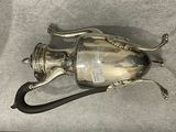 a silver tea pot with a black handle on a table