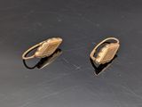 une paire de boucles d'oreilles dorées posées sur un fond noir