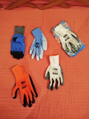 cinq paires de gants de jardinage posées sur un lit, à côté d'une paire de gants