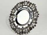 une plaque d'argent ornée d'un motif sur une surface blanche