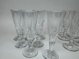 six clear wine glasses are lined up on a white surface