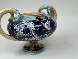 a blue and gold vase with two handles on a white surface