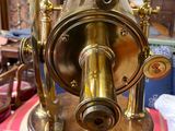 un télescope en laiton posé sur un socle en bois dans une pièce