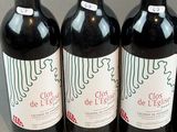 four bottles of red wine are lined up on a table