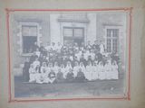an old photo of a group of people sitting in front of a building
