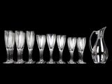 several empty wine glasses and a pitcher on a black background