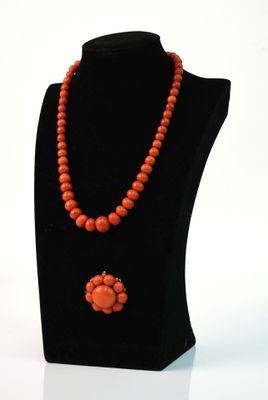 collier de perles orange orné d'un pendentif en forme de fleur, porté par un mannequin noir