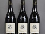 three bottles of wine are lined up on a table