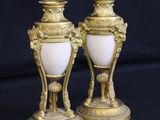 pair of antique brass and white glass vases sitting on a black background