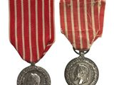 deux médailles ornées d'un ruban rouge et une médaille d'argent sur fond blanc