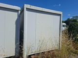 deux conteneurs de stockage blancs posés au milieu d'un champ