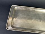an antique silver tray with beaded edges on a black surface
