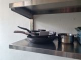 stainless steel shelf with pots and pans on it in a kitchen