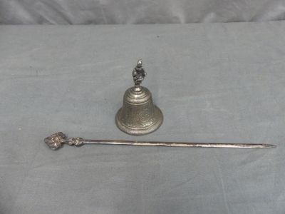 a silver bell and a spoon sitting on a table