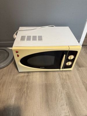 a microwave that is sitting on the floor next to a trash can
