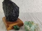 a rock on a wooden stand next to some green crystals