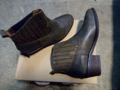 pair of men ' s brown leather boots sitting on top of a cardboard box