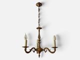 an antique brass chandelier with three candles hanging from the ceiling