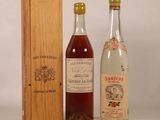 two bottles of alcohol sit next to a wooden box on a white surface