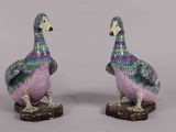 pair of colorfully painted ceramic ducks sitting on top of a wooden base