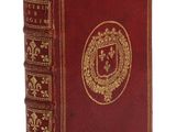 un vieux livre rouge aux tranches dorées, orné d'un blason sur la couverture