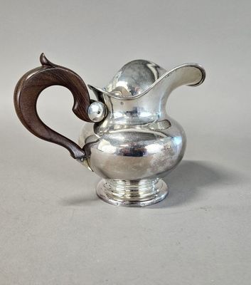 une théière en argent avec une poignée en bois posée sur une table