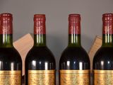 three bottles of red wine are lined up on a shelf