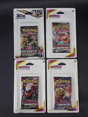 Trois paquets de cartes à collectionner Pokémon sont posés sur une table noire.
