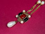 a close up of a necklace with pearls on a pink surface