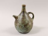 a green vase with a handle on a white surface